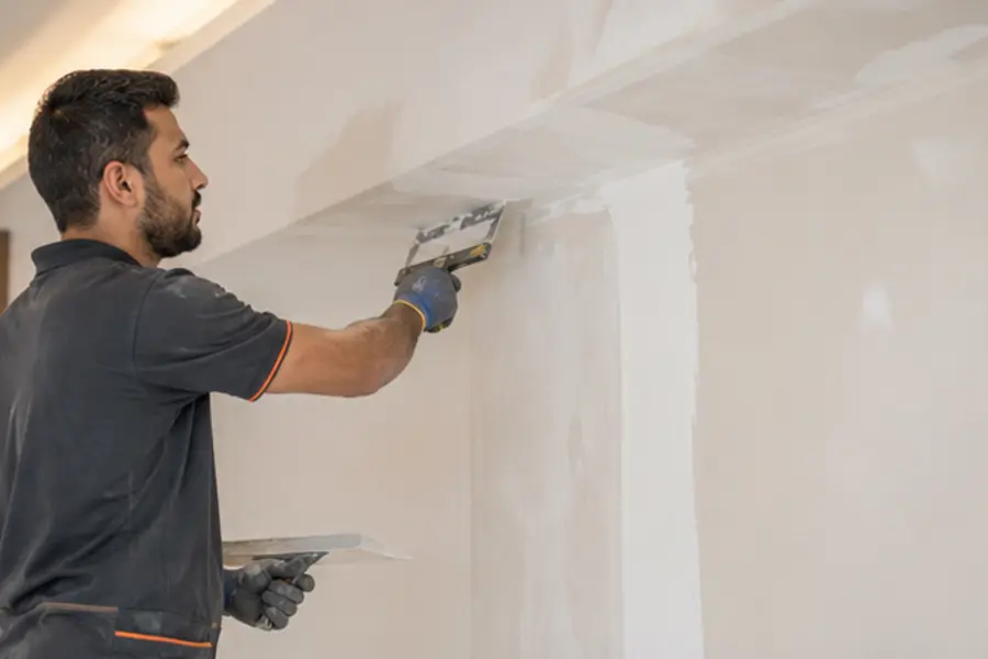 Technician completing smooth wall and ceiling finishing